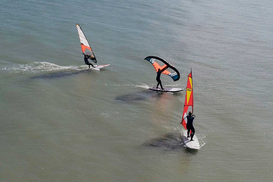Drei Windsurfer stehen auf dem Wasser