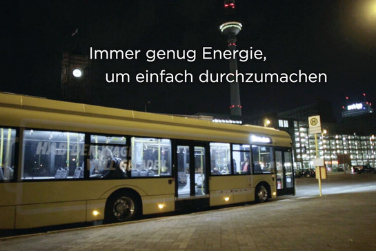 Nachts in Berlin, ein Stadtbus steht an einer Haltestelle. Im Hintergrund der Fernsehturm. 