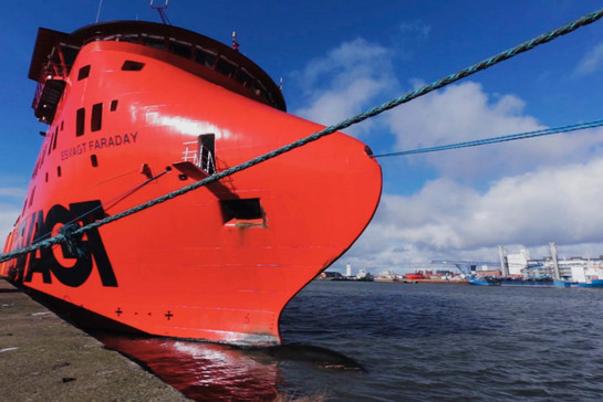 Ein rotes Containerschiff legt am Hafen an