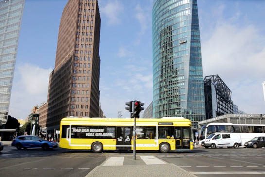 Ein gelber Stadtbus fährt über eine Kreuzung in der Stadt.