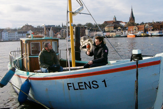 Mads Schreiner sitzt auf einem Boot mit Timo Klass