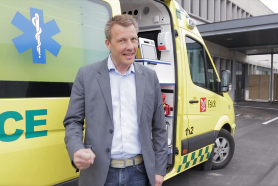 Ein Mann steht vor einem gelben Krankenwagen