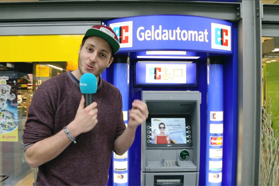 Lars steht vor einem Geldautomaten