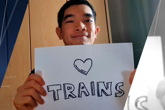 Ein Mann hält ein Schild mit "I love trains" in der Hand.