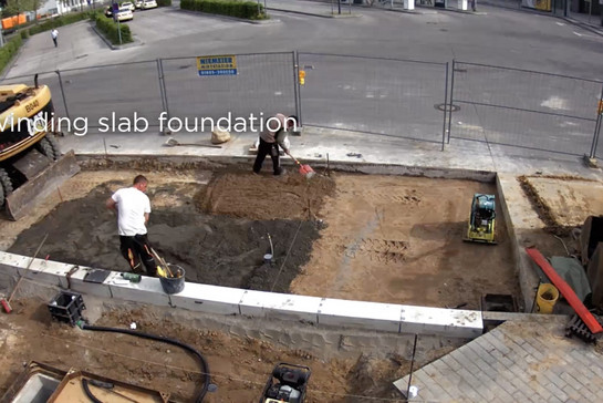 Baustelle an einer Bushaltestelle, zwei Männer bearbeiten das Fundament. 
