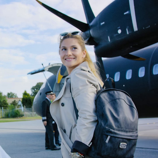 Eine blonde Frau trägt einen schwarzen Rucksack am Flughafen