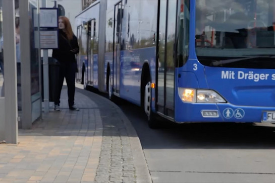 Ein blauer Bus hält an einer Haltestelle