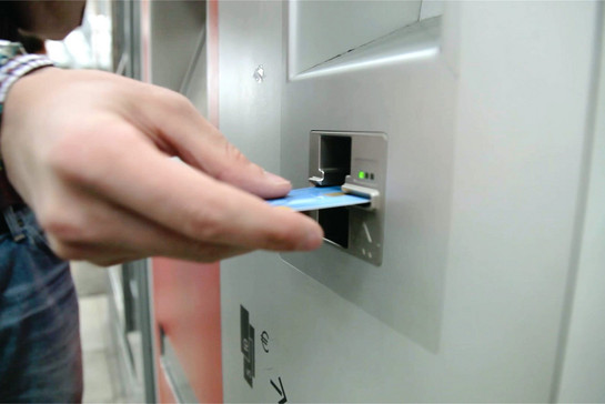 Lars schiebt eine Bankkarte in einen Ticketautomaten