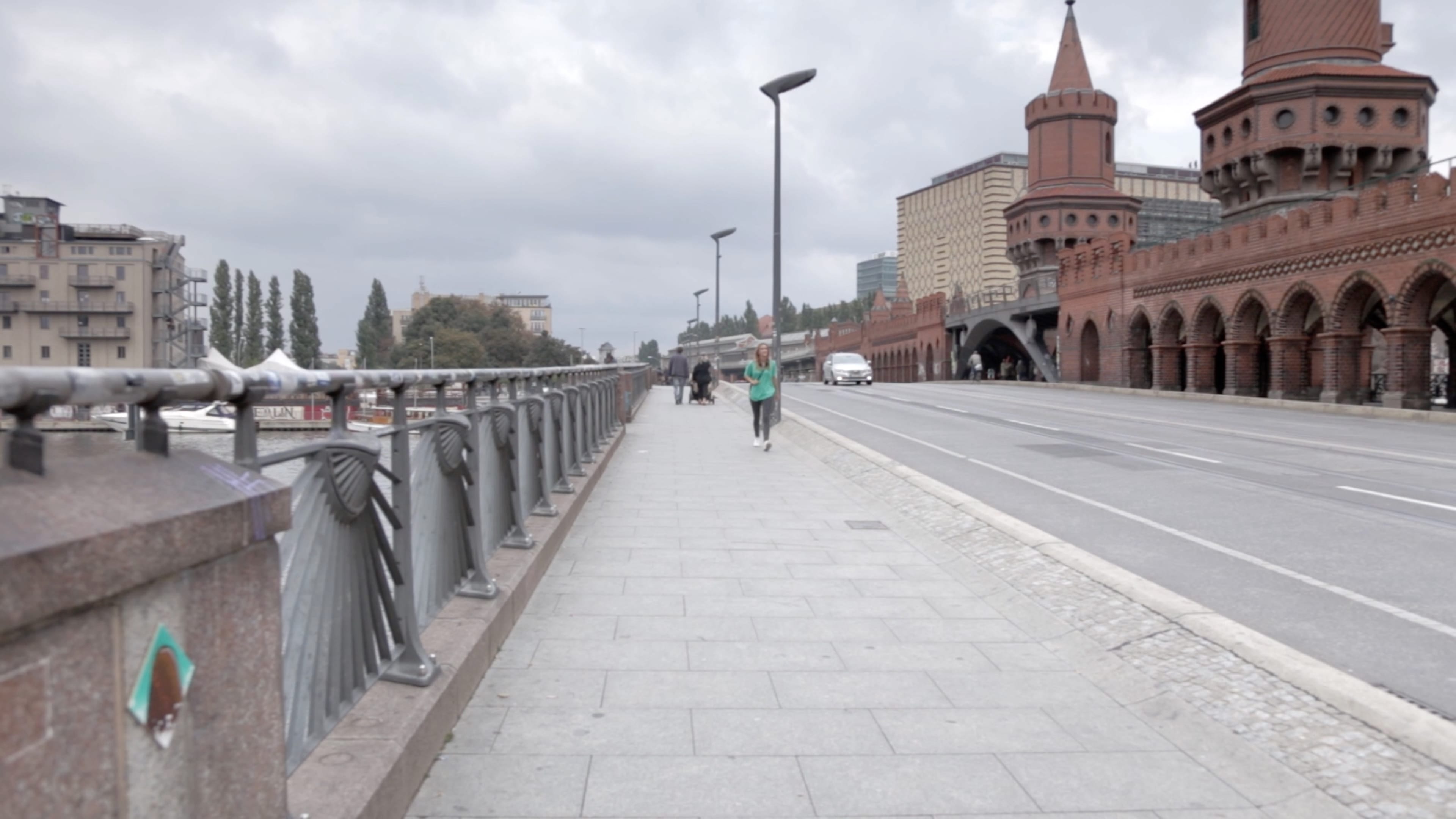 Fußgänger und ein Auto auf einer Brücke in Berlin. 