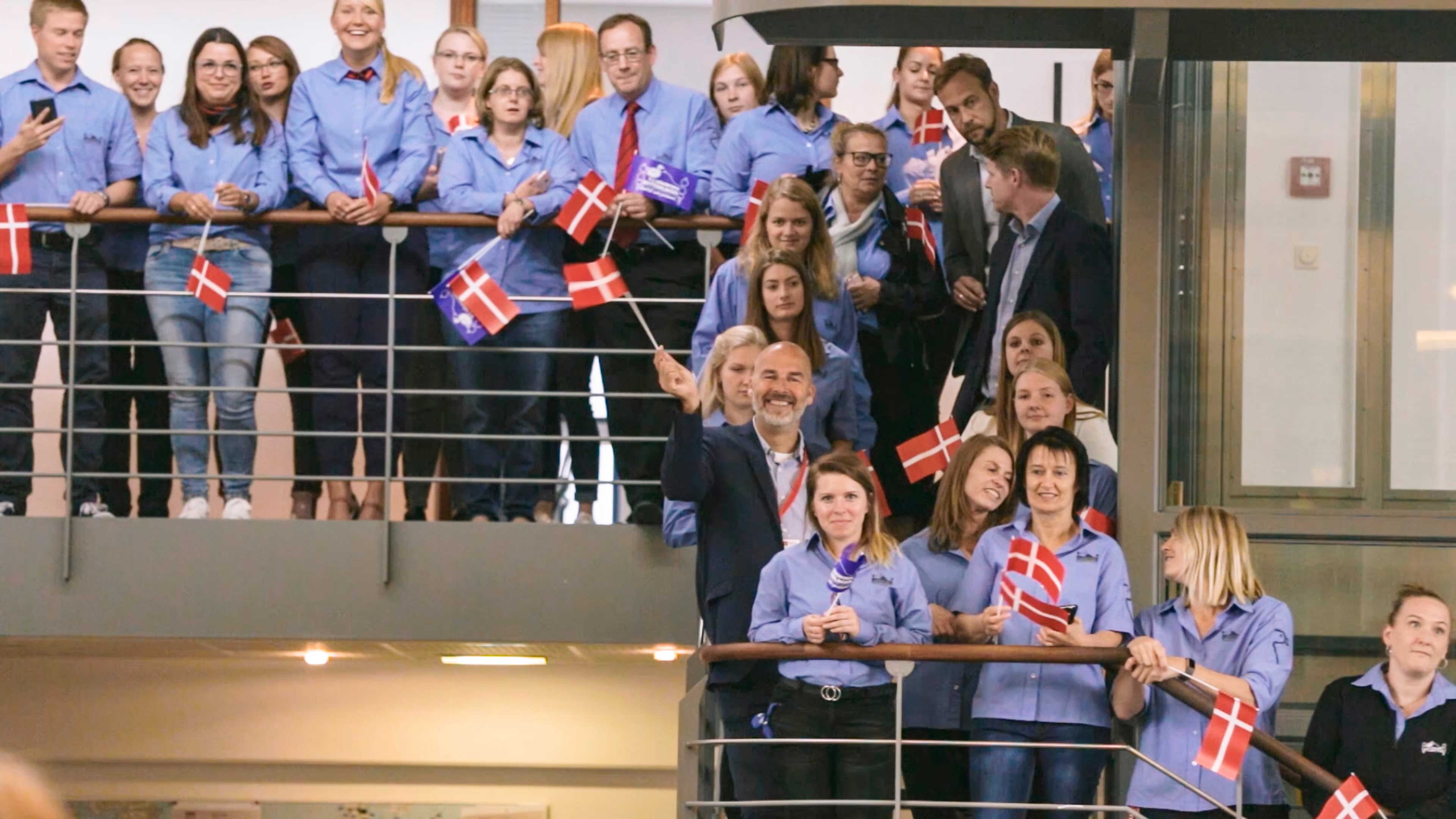 Mitarbeiter des dänischen Bettenlagers stehen mit dänischen Flaggen auf einer Treppe