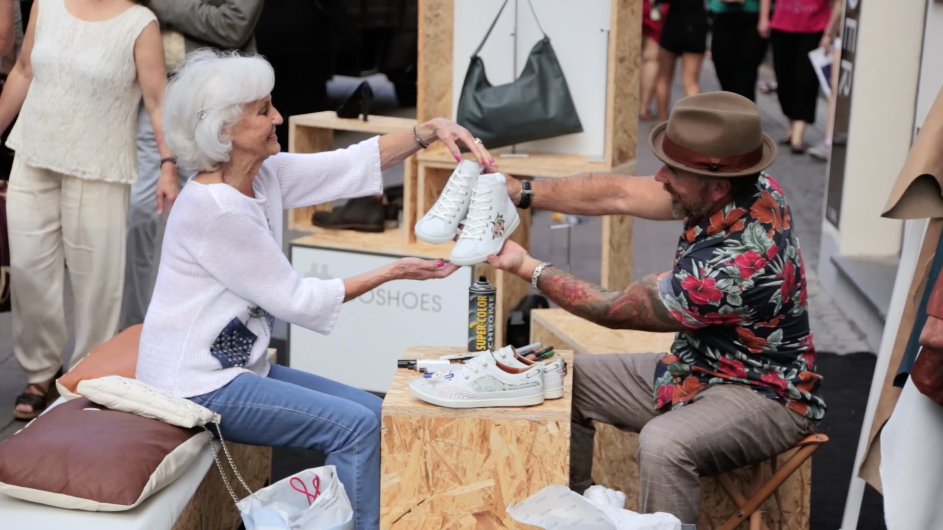 Ein Ecco Verkäufer überreicht einer älteren Dame ein paar Sneaker