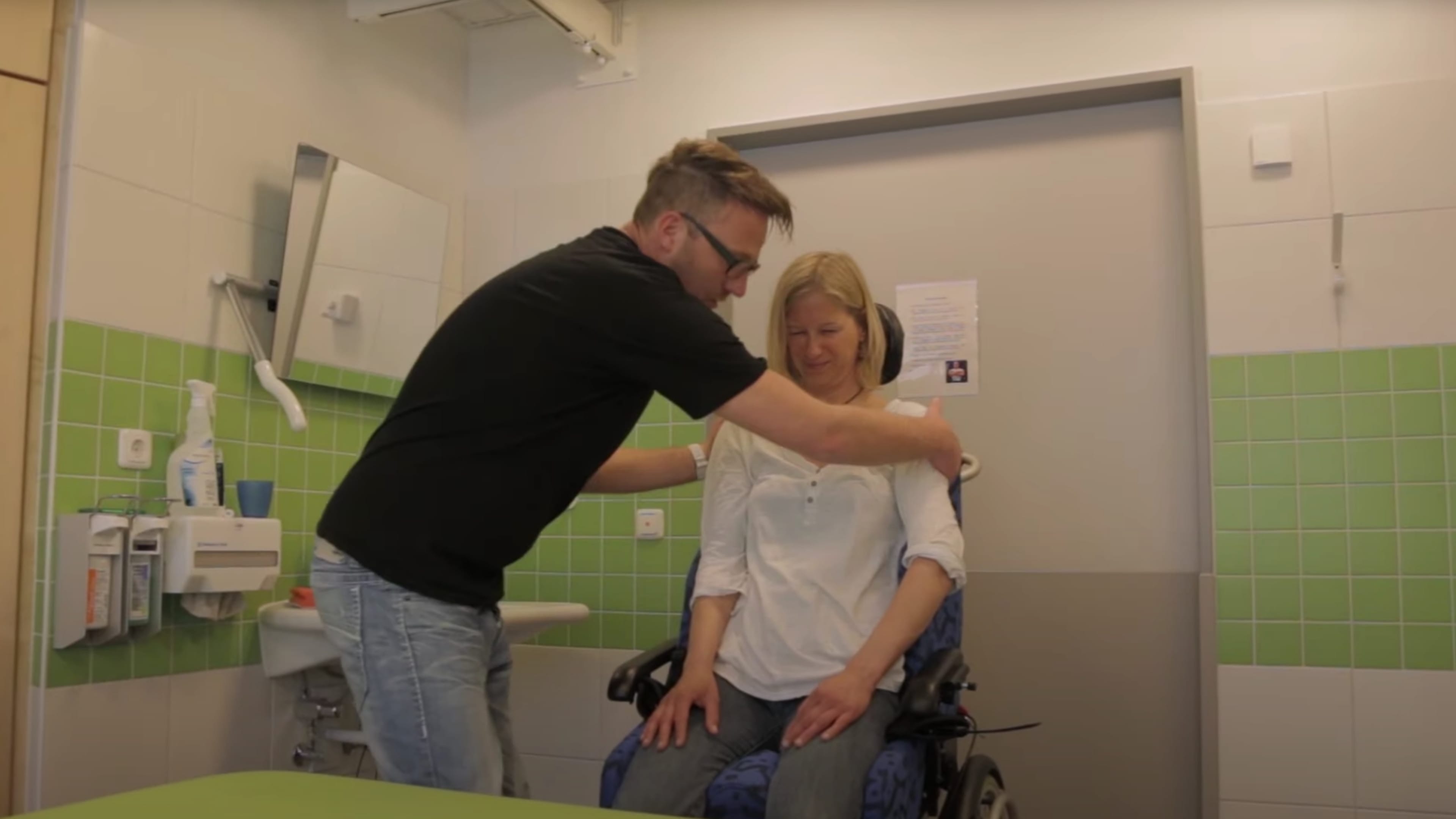 Ein Mann hilft einer Frau aus dem Rollstuhl