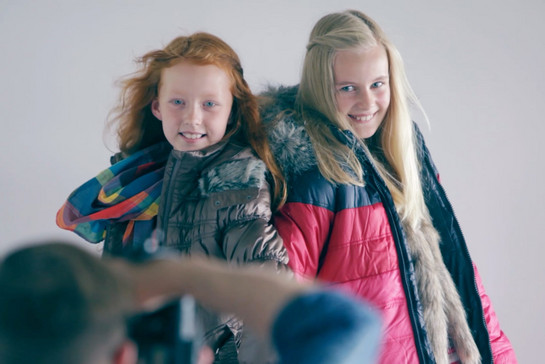 Ein Fotograf fotografiert zwei junge Mädchen, die Winterkleidung tragen.