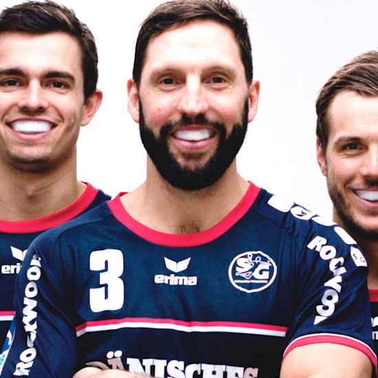 Drei Handballspieler tragen einen Mundschutz