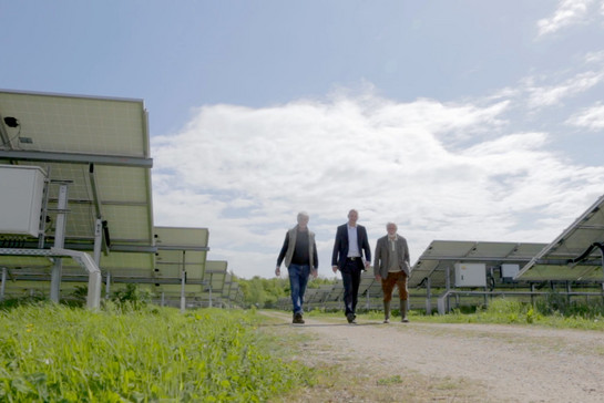 Drei Männer gehen durch einen Solarpark