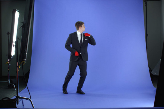 Ein Mann im Anzug und roten Handschuhen posiert vor der Kamera