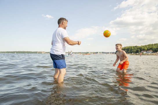 Ein Vater und sein Sohn spielen Ball im Wasser