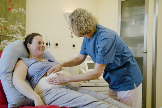 Eine Krankenschwester tastet den Bauch einer schwangeren ab