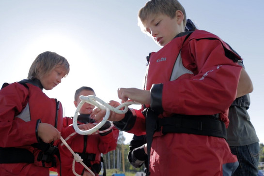 Drei Kinder üben einen Knoten zu binden