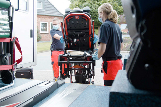 Zwei Rettungssanitäter schieben eine Patienten in den Rettungswagen