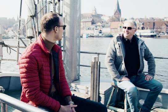 Zwei Männer unterhalten sich auf einem Kutter im Flensburger Hafen