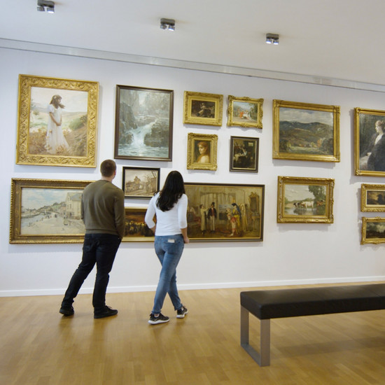 Zwei Personen schauen sich alte Gemälde an einer Museumswand