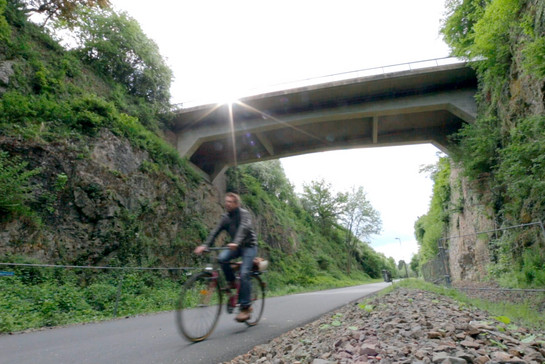 Ein Radfahrer fährt unter eine Brücke