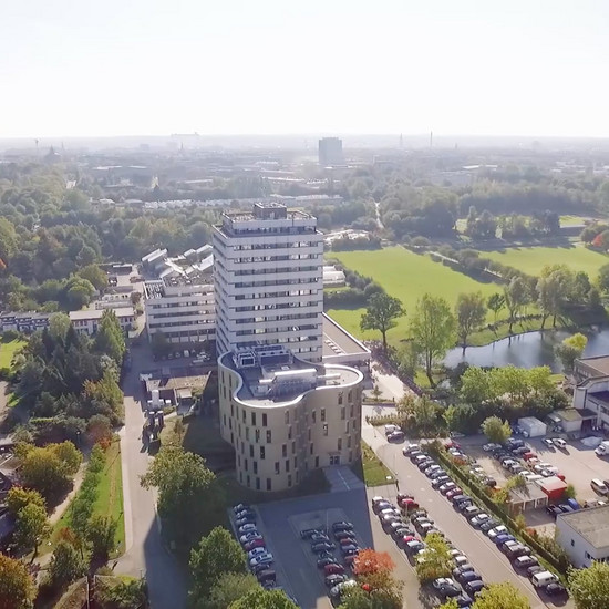 Luftaufnahme eines großen Gebäudes, davor ein Parkplatz. Es könnte die Universität in Kiel sein. 