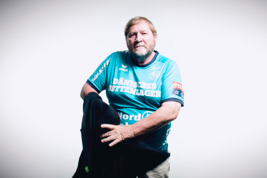 bb_eri_teaser_04.jpg Ein älterer Mann trögt ein blaues SG Shirt