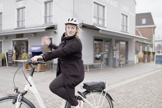 bb_ggf_teaser_06.jpg Eine blonde Frau mit weißen Sturzhelm fährt Fahrrad