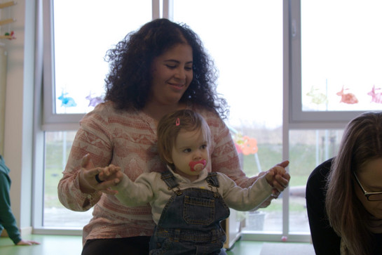 bb_kita_teaser_04.jpg Eine Kindergärtnerin hält die Arme eines Kindes