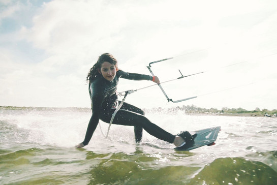 Eine Kitesurferin streift das Wasser beim kiten