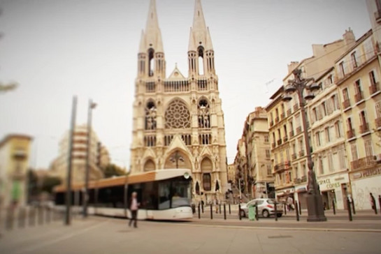 Eine S-Bahn in einer südfranzösischen Stadt, sie fährt an einer Kirche vorbei.