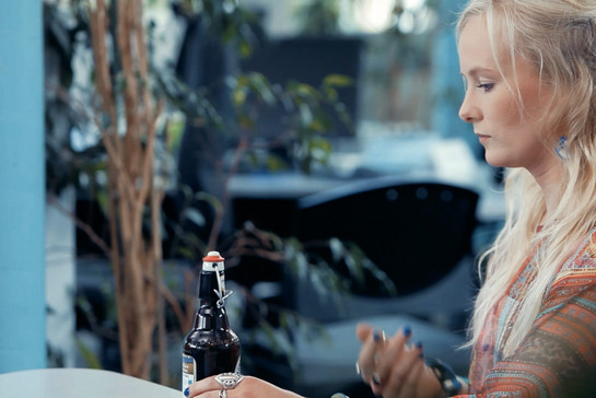 Eine blonde Frau hält ein Bier in der Hand