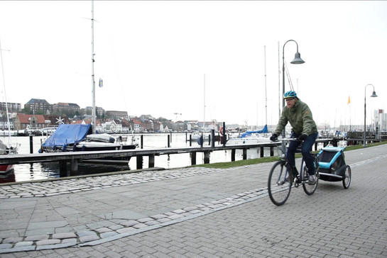 Ein Mann fährt mit seinem Fahrrad am Flensburger Hafen lang