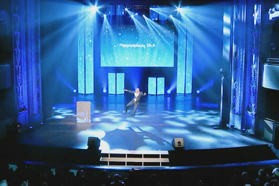 Ein Mann tanzt auf der Bühne zu einer blauen Lichtershow