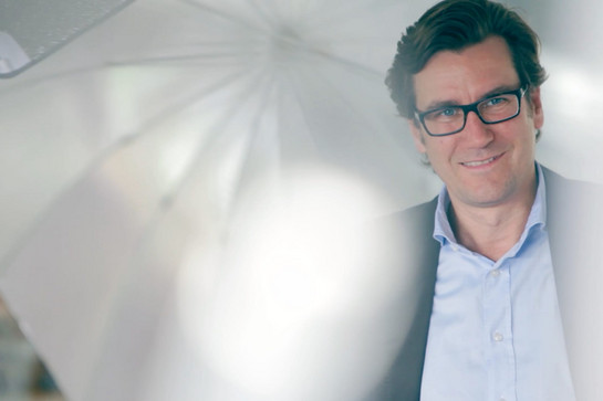 bb_modelbehrens_teaser_02.jpg Mann mit Brille, er trägt ein hellblaues Hemd und lächelt.