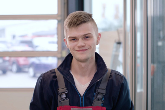 Ein junger KFZ Mechaniker lächelt in die Kamera