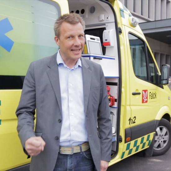 Ein Mann steht vor einem gelben Krankenwagen
