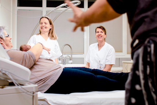 bb_outtakes_teaser_03.jpg Eine Frau liegt auf einem Krankenbett und hält ein Baby im Arm