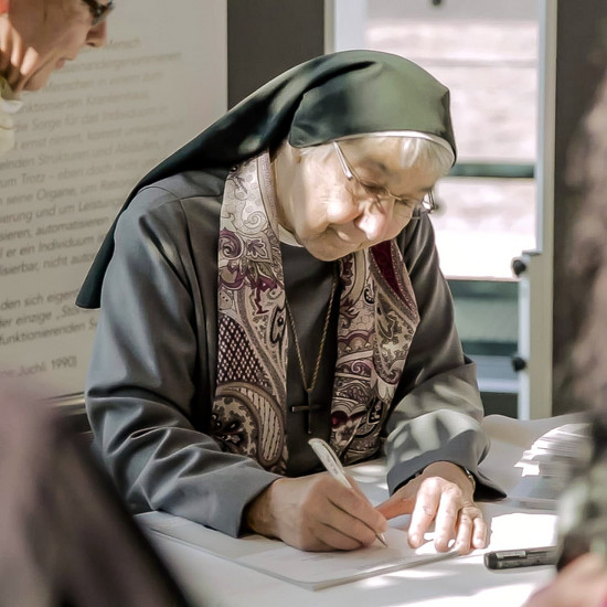 Eine Nonne unterschreibt ein Papier