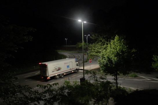 Ein weißer LKW fährt Nachts auf einer Straße