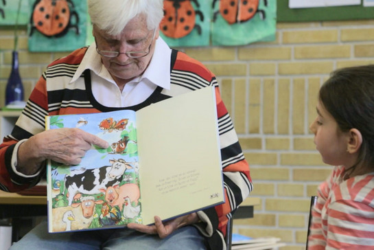 Eine alte Dame zeigt Kindern ein Kinderbuch