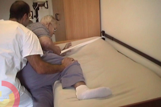 Ein Pfleger hilft einer Pflegebedürftigen Frau ins Bett