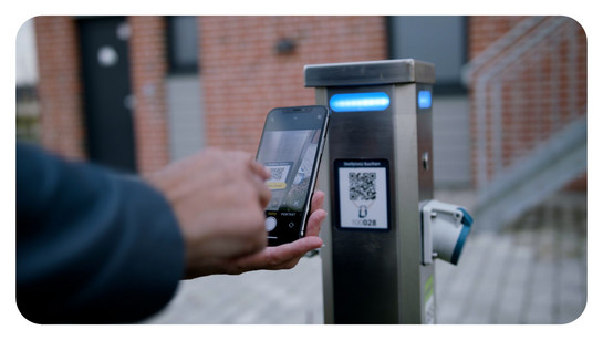 Eine Person scannt einen QR Code vom WDR Stellplatzautomaten