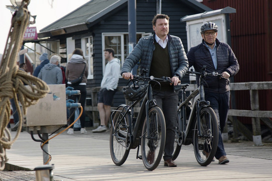Zwei Männer schieben ihre Fahrräder im alten Flensburger Museumshafen