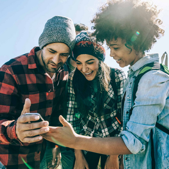 Hallo Netzwerk! Drei Personen schauen auf Smartphone