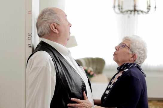 Ein altes Ehepaar misst ihre Körperhöhe am Türrahmen