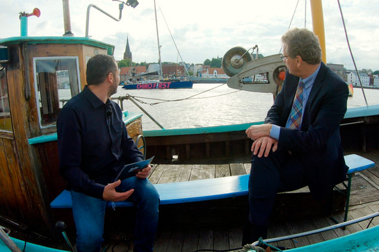 bb_buchholz_teaser_06.jpg Bernd Buchholz und Timo Klass schauen auf ein vorbeifahrendes Segelboot