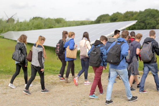Eine Schulklasse geht durch einen Solarpark